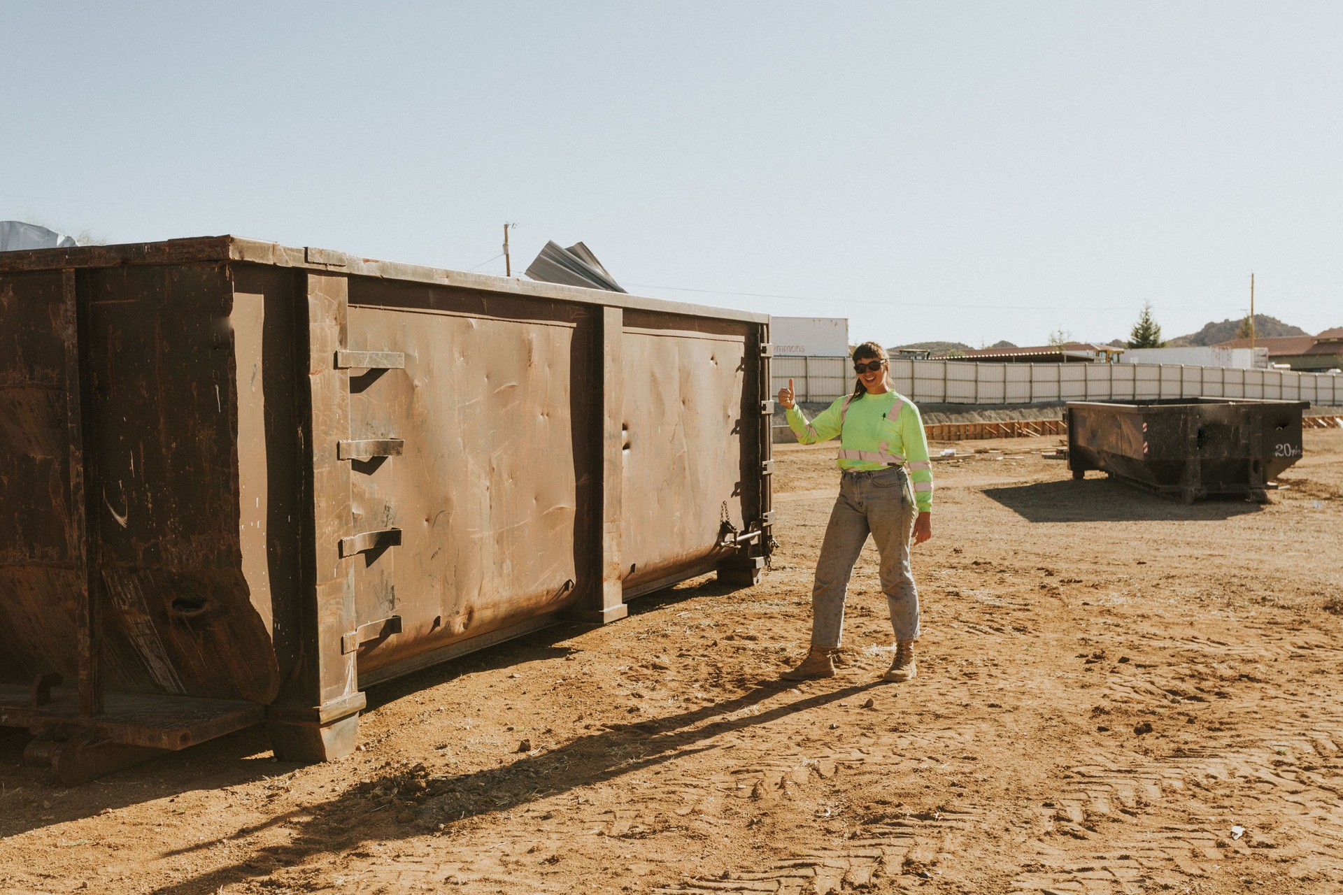 Construction woman throwing items in giant dumpster